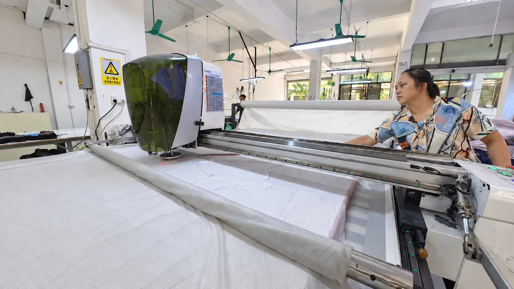 Automatic fabric cutting machine with an operator in the cutting room at the Humen factory