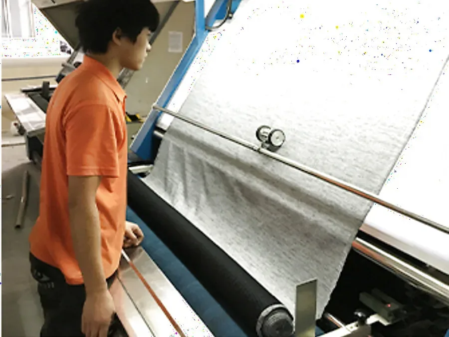 An operator beside fabric inspection equipment in the Jiashun factory in Humen, Dongguan