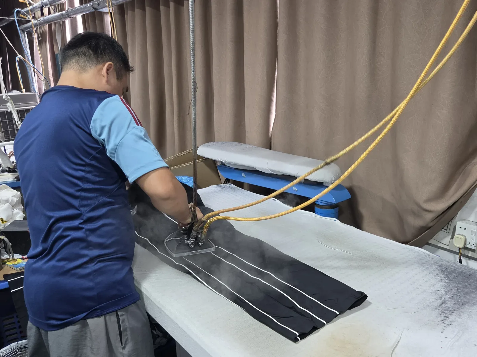 Operator steam-pressing a garment at the Humen factory